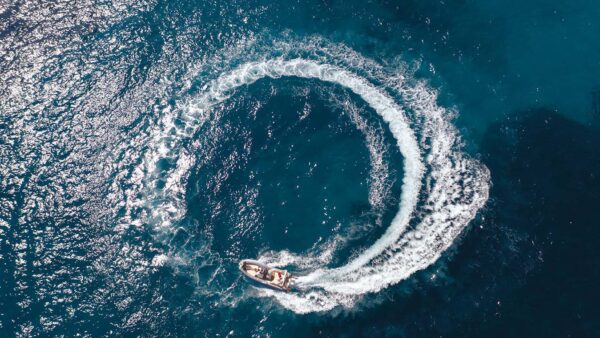 Scatto aereo di un gommone Joker Boat - Clubman 28 in mare aperto, tracciando un cerchio perfetto nell’acqua smossa al suo passaggio.