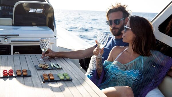 Scatto con dettaglio della dinette di un gommone Joker Boat - Clubman 35, mentre una coppia di gusta un aperitivo.